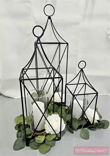 Set of 3 Metal Lanterns, Black: each set will get a 24",19",13" Lantern with eucalyptus candle rings that will fit glass vases. **VASES WILL NEED TO BE ADDED SEPERATELY, 6.25",7.5",9"**